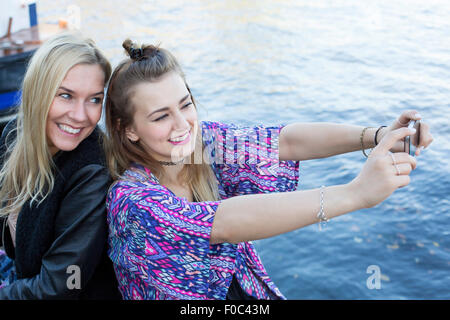 two women by the waterfront taking a selfie Stock Photo