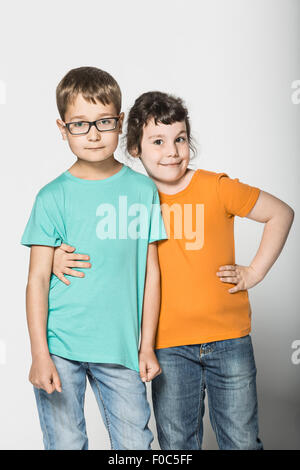 Portrait of brother and sister standing arm around against white background Stock Photo