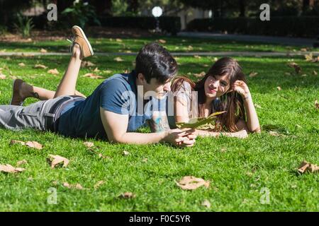 Young couple with autumn leaf lying in park Stock Photo