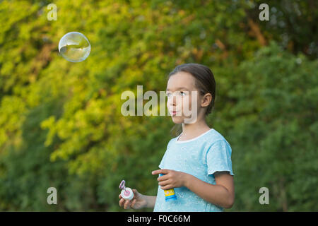 Happy girl blowing bubble outdoors Stock Photo