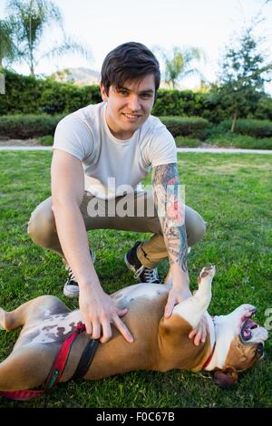 Portrait of young man in park playing with bulldog Stock Photo