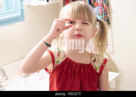 Portrait of young girl, looking through fingers Stock Photo