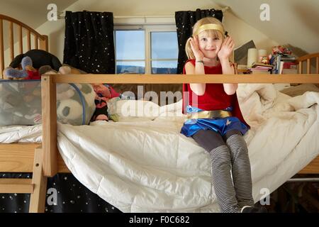 Portrait of young girl, sitting on bed, wearing fancy dress costume
