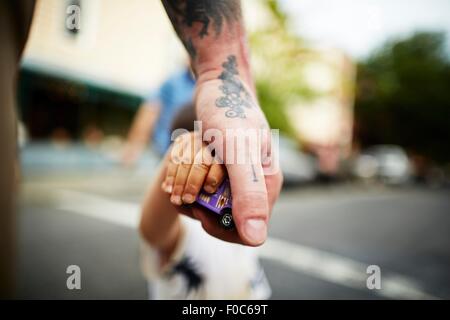 Close up of man holding boy's hand and toy crossing road Stock Photo