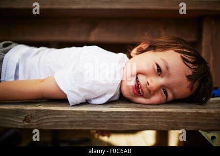 Portrait of smiling boy laying on bench Stock Photo