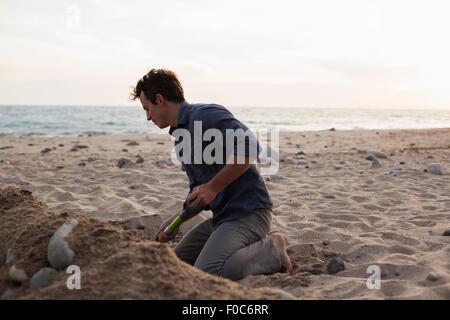 Man digging into sand on beach Stock Photo