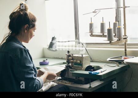Young female seamstress sewing textile on sewing machine Stock Photo