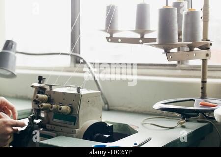 Hands of young female seamstress sewing textile on sewing machine Stock Photo