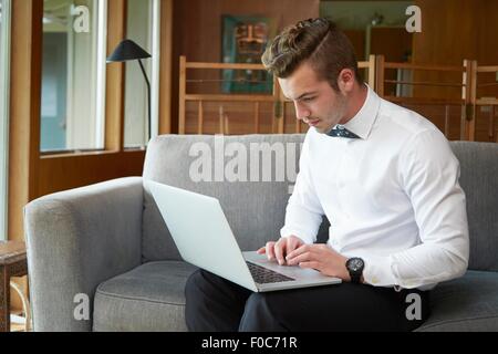 Portrait of man sitting on sofa working from laptop Stock Photo