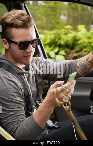 Portrait of man driving wearing sunglasses and using smart phone Stock Photo