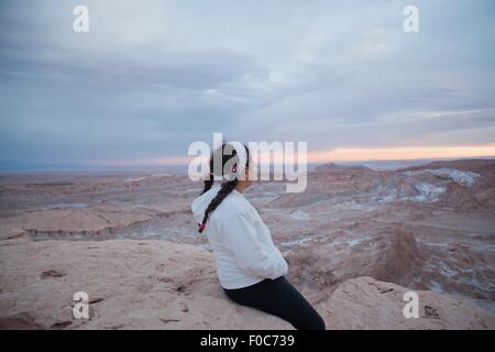 Young girl sitting on rock looking at view, Valley of the Moon, San Pedro. Atacama. Chile Stock Photo