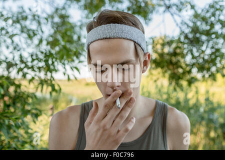 Young man smoking outdoors Stock Photo