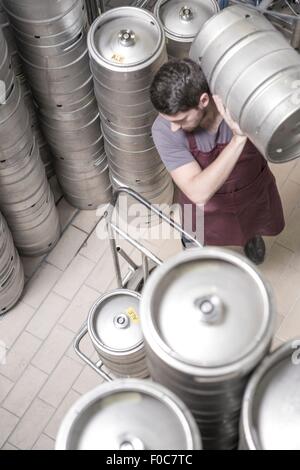 Brewer moving kegs in brewery Stock Photo