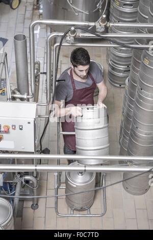 Brewer moving kegs in brewery Stock Photo