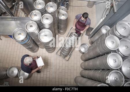 Brewers moving kegs in brewery Stock Photo