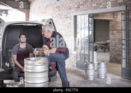 Brewers loading kegs into back of van Stock Photo