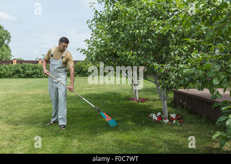 Full length of young man with rake cleaning lawn Stock Photo