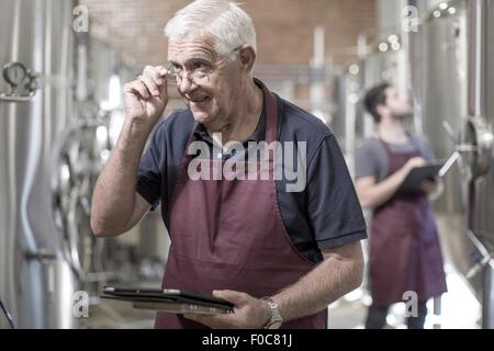 Brewers in brewery standing next to stainless steel tanks Stock Photo