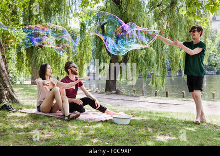 Happy friends enjoying with large bubble at park Stock Photo