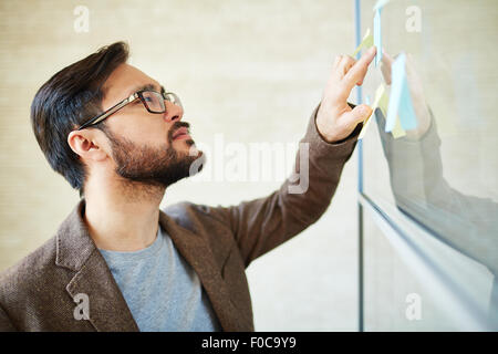 Young businessman reading note on sticker Stock Photo
