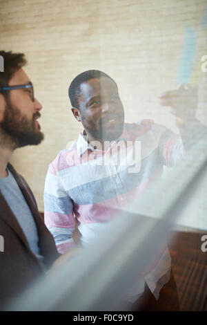 African businessman showing note on board to his colleague Stock Photo