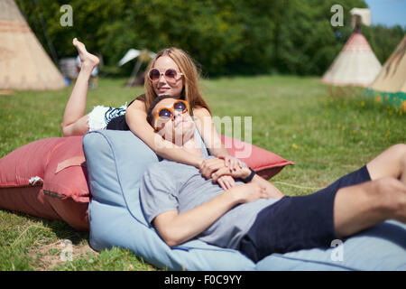 Young couple lying on pillows while glamping, teepee in background Stock Photo