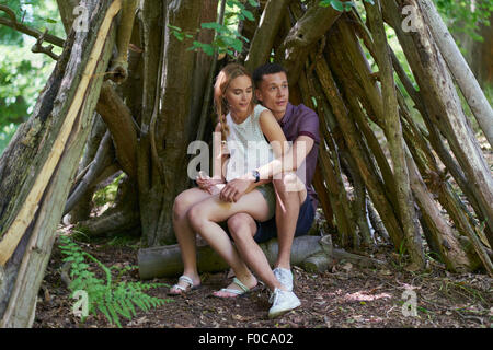 Young woman sitting on man's lap under logs in park Stock Photo