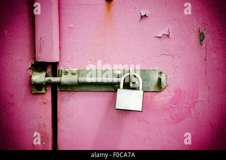 Rusty padlock on old pink painted wooden door Stock Photo