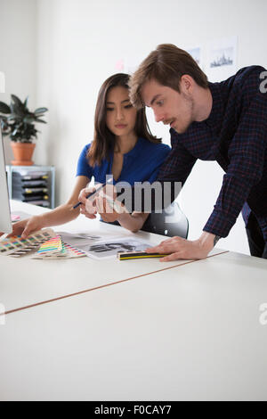 Young business colleagues discussing over swatches at desk Stock Photo