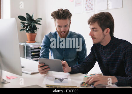 Young businessmen using digital tablet together at desk Stock Photo
