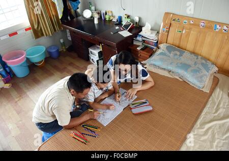 (150812) -- NANNING, Aug. 12, 2015 (Xinhua) -- The 7-year-old child Mei Mohan, coming from east China's Jiangxi Province, draws pictures with his parents at a construction site in Nanning, capital of south China's Guangxi Zhuang Autonomous Region, Aug. 12, 2015. Nearly one thousand builders from across the country work at the Lianqing Bridge construction site in Nanning City, far away from their children and home. Some children can't wait until Spring Festival, the only time for their parents to return home, but came to Nanning for reunion during their summer vacation. (Xinhua/Lu Boan) (mt) Stock Photo