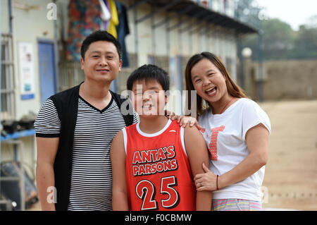 (150812) -- NANNING, Aug. 12, 2015 (Xinhua) -- The 12-year-old boy Zhang Ji, coming from east China's Jiangxi Province, poses with his parents at a construction site in Nanning, capital of south China's Guangxi Zhuang Autonomous Region, Aug. 12, 2015. Nearly one thousand builders from across the country work at the Lianqing Bridge construction site in Nanning City, far away from their children and home. Some children can't wait until Spring Festival, the only time for their parents to return home, but came to Nanning for reunion during their summer vacation. (Xinhua/Lu Boan) (mt) Stock Photo