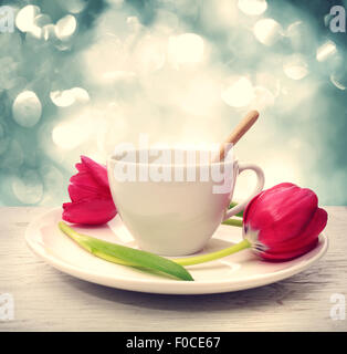 Coffee cup with red tulips over blue shiny background Stock Photo