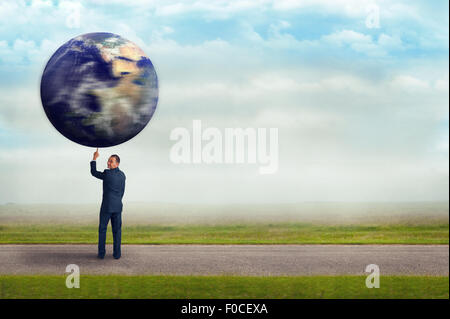 businessman holding spinning planet earth globe aloft with one finger Stock Photo