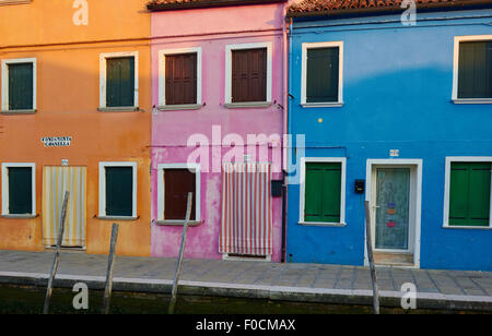 Dawn sunlight begins to light up the colourful facades of canalside painted houses Burano Venetian Lagoon Veneto Italy Europe Stock Photo