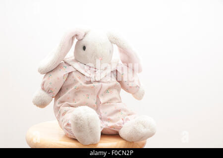 Retro stuffed bunny sitting on a stool with a white background. Stock Photo