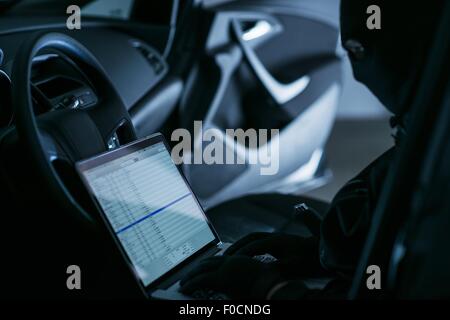 Hacker with Laptop in a Car at Night. Hacking WiFi Networks From Remote Location. Stock Photo