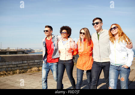 happy teenage friends walking along city street Stock Photo