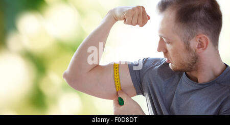 close up of male hands with tape measuring bicep Stock Photo