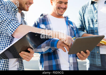 group of smiling builders with tablet pc outdoors Stock Photo