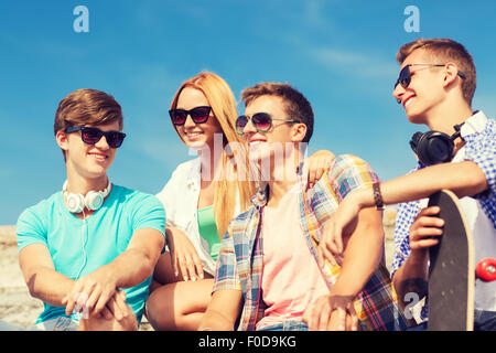 group of smiling friends sitting on city street Stock Photo