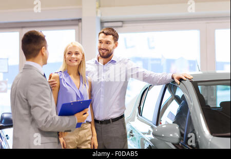 happy couple with car dealer in auto show or salon Stock Photo