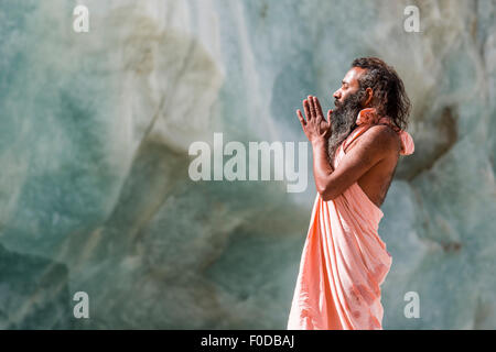 A Sadhu, holy man, is standing and praying on a block of ice at Gaumukh, the main source of the holy river Ganges, Gangotri Stock Photo