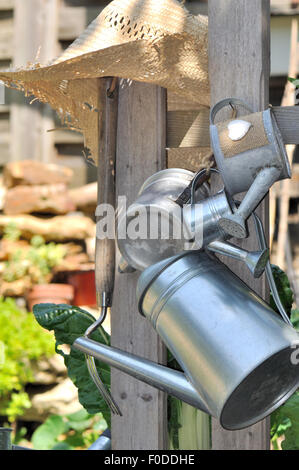 various metal watering cans hung on a fence in garden Stock Photo