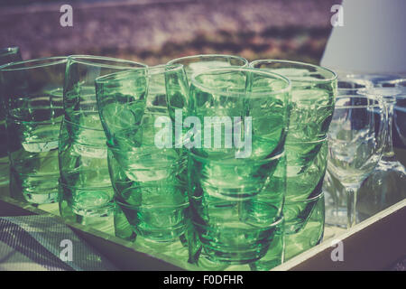 Green clear glasses stacks on the table in a cafe. Filtered shot Stock Photo