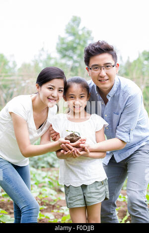 Young family holding a seedling together Stock Photo