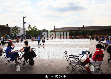 People sit around the fountains in Granary Square outside Central Saint Martins Stock Photo