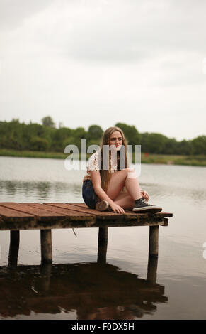 Pretty teenage girl sitting on the baordwalk on a cloudy day Stock Photo