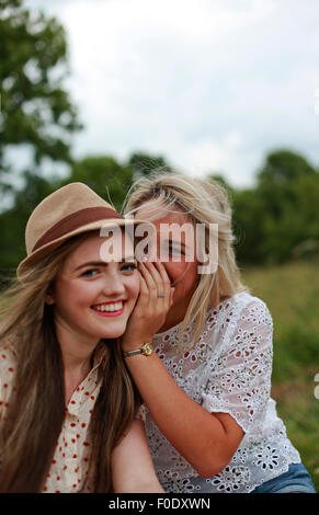 Two teenage girls one whispering to the other Stock Photo