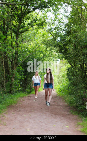 Two teenage girls walking down a country lane in summer Stock Photo
